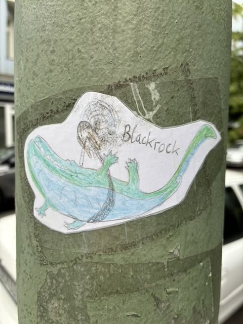 Ein gezeichneter Blauwal, der von einem Hubschrauber mit einem Gurt durch die Luft getragen wird. Darüber steht „Blackrock“.